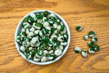 White Bowl of Hot and Spicy Wasabi Peas on an oak tableの写真素材