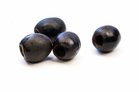 Closeup of Four Black Olives on a White Backgroundの写真素材