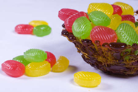 Caramel vase with colored candy on a white background
