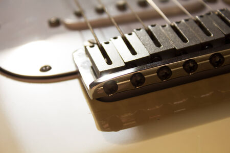 close up of the bridge of a strat, daytime,  white guitar