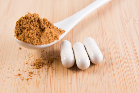 spoon with guarana and three coffein-tablets on a wooded plate の写真素材