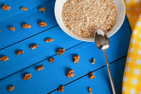 Bowl of fresh oatmeal walnuts on teal rustic table, hot and healthy food for Breakfastの写真素材