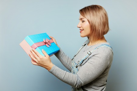 Girl with gift box in her hands on a blue background.