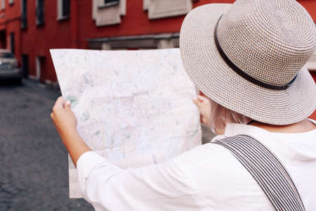 Travel guide. Young female traveler with backpack and with map on the street. Travel concept