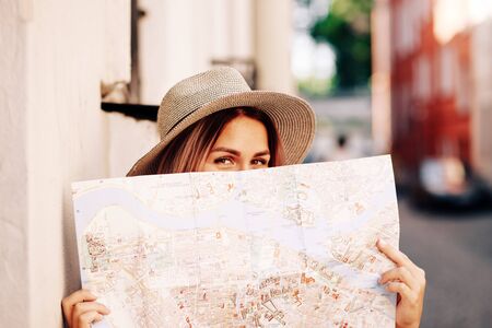 Travel guide. Young female traveler with backpack and with map on the street. Travel concept