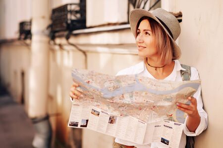 Travel guide. Young female traveler with backpack and with map on the street. Travel concept