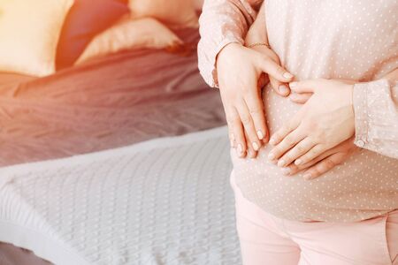 Pregnant woman and her husband hugging the tummy.