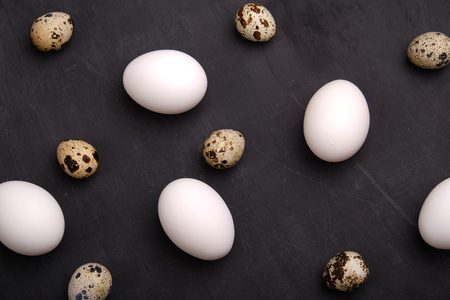 Chicken and quails eggs on black background