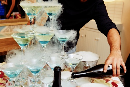 Catering service. Wedding slide champagne for bride and groom outdoors. Colorful glasses for alcohol. Business, catering service. Catering bar for celebration. Beauty of interior for wedding dayの写真素材