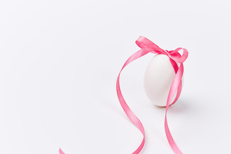 Easter Egg with pink ribbon Bow on white backgroundの写真素材