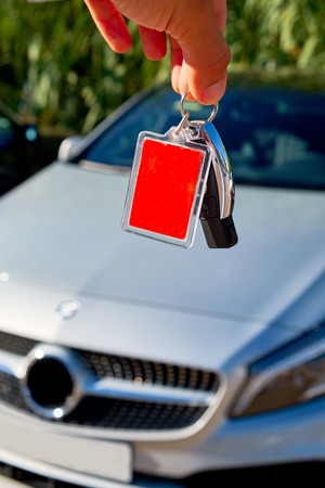 Male holding car keys with car on backgroundの写真素材