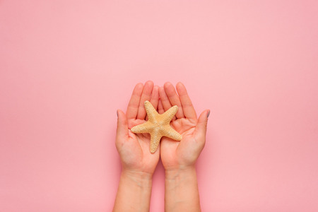 Hands holding starfish. Symbol of summer, relaxation on the beach. Trendy summerの写真素材