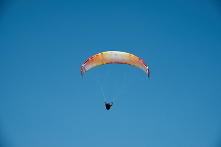 Paraglider is flying in the blue sky. Paragliding in the sky on a sunny day