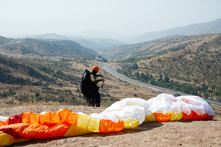 Man paraglider taking off from the edge of the mountain. Paragliding sports.の写真素材