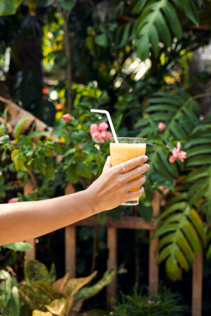 Hand Hold Healthy Pineapple Smoothie Cocktail. Yellow Detox Fresh Shake Drink for Breakfast Wellness Nutrition. Tropical Banana Coconut Mix. Organic Summer Exotic Fruit Juice Blend Outdoor Side Viewの写真素材