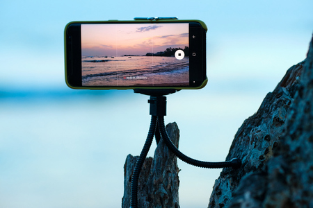 Time-lapse Recording Sunset and Sea on Smartphone. Extreme Version of the Cinematography Technique of Undercranking. Stop Motion Animation. Wood, Beach and Fishermen in Boats on Imageの写真素材