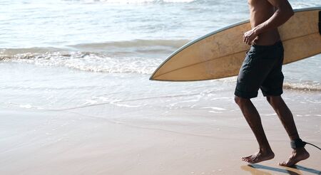 Man Surfer Sitting at Surfboard on Sand Beach. Happy Mulatto Guy Pose on Tropical Summer Ocean Coast...