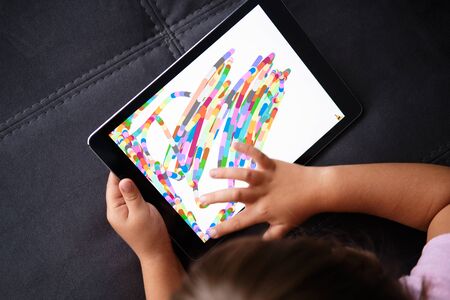Preschool Girl Draws on the Tablet. Little girl play with tablet.の写真素材