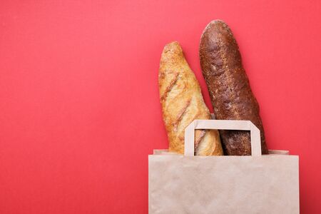 Fresh bread and baguette in paper bag on the red background. Bak