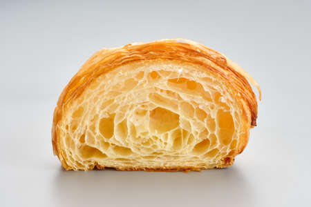 Fresh baked croissant unfilled cutaway on a light grey backgroundon. Airy porous structure of a croissant without filling. Macro photography.の写真素材