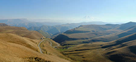 Caucasus mountains in autumn. Elbrus is visible in the distance in a light haze. Beautiful mountain...
