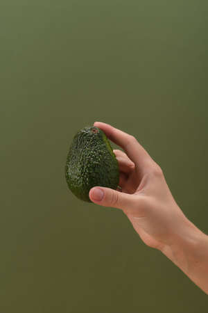 Fresh avocado in a humans hand. Healthy food and vegetarianism concept. Front view.