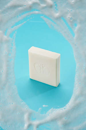 Baby soap of white color on a blue background with soap foam. View from above.の写真素材