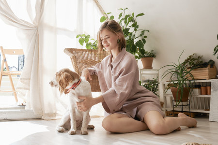 Smiling cute girl in pajamas in the morning with dog at home. Front view.