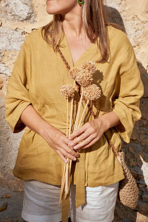 Girl holding a bouquet of amazing dry plants. Wonderful combination of colors. Front view.