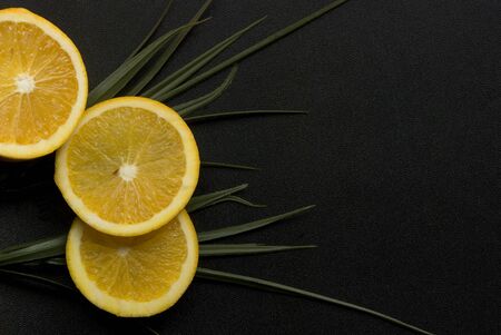 Fresh orange slices with green leaves in a black backgroundの写真素材