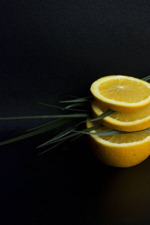 Fresh orange slices with green leaves in a black backgroundの写真素材