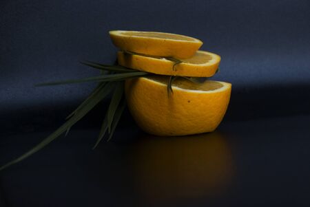 fresh orange slices and green leaves in a dark backgroundの写真素材
