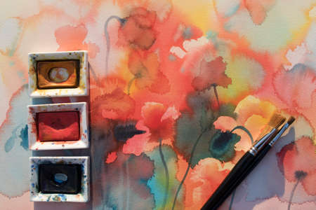 Color pans with brushes on poppies watercolor background