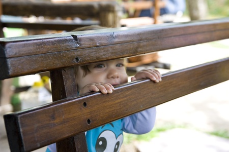 a cute baby looking back of a wooden bankの写真素材
