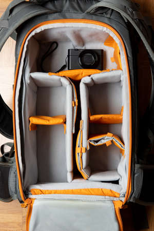 Minimalist travel photographer concept. Top view of a big photography backpack with a small compact camera inside.の写真素材