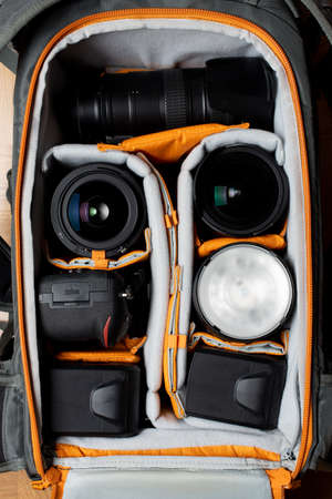 Top view of a big photography backpack showing the DSLR gear. A camera body, few lenses and lighting...