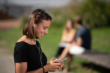 Portrait of a smiling brunette girl chatting on her phone.の写真素材