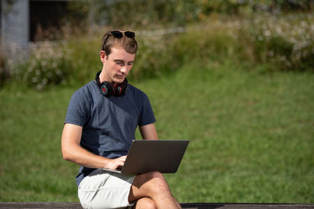 Handsome young blond man working on his computer outdoorsの写真素材