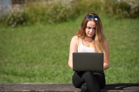 Pretty teenager serious and concentrated girl working on her laptop with a green backgroundの写真素材