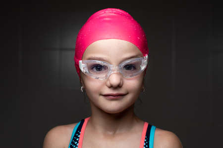 Closeup portrait of a little smiling swimmer girl with dark background.の写真素材