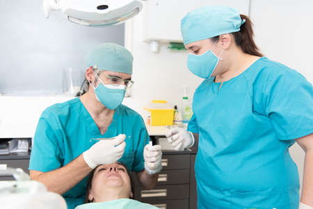 Dentist and an assistant nurse treating a patient.の写真素材