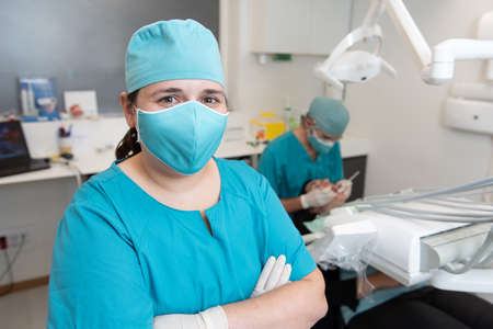 Portrait of an assistant nurse in a dental clinic office with the dentist working behind.の写真素材