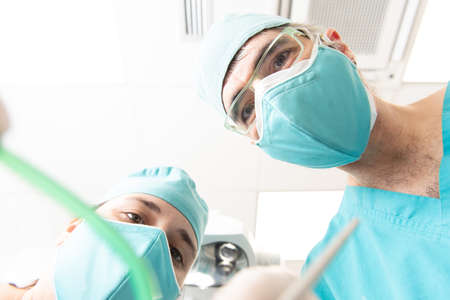 View of a patient while a dentist and his assistant nurse are exploring and making a check up of his mouth, with copy space.の写真素材