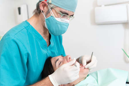 Dentist making a basic check up to a female patientの写真素材