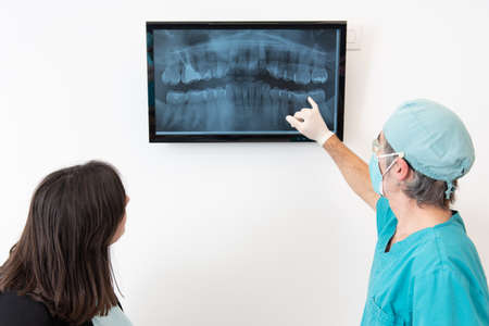 Dentist explaining something to a patient using a digital x-ray radiographyの写真素材
