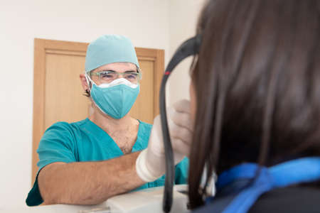 A smiling dentist preparing a patient to have a panoramic dental radiography using double mask during Coronavirus pandemic.の写真素材