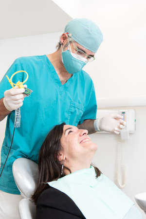 Dentist and smiling patient looking each other while putting an x-ray tool.の写真素材