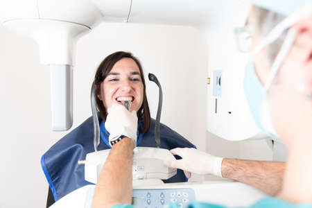 A dentist preparing a smiling patient to have a panoramic dental radiographyの写真素材