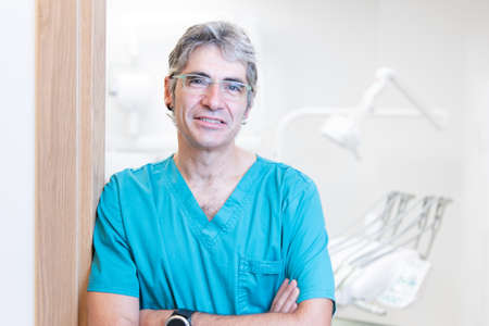 Portrait of a male dentist with medical tools behind.の写真素材