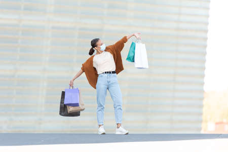 Shopping during Coronavirus pandemic concept. A happy and proud young woman holding her shopping bags.の写真素材